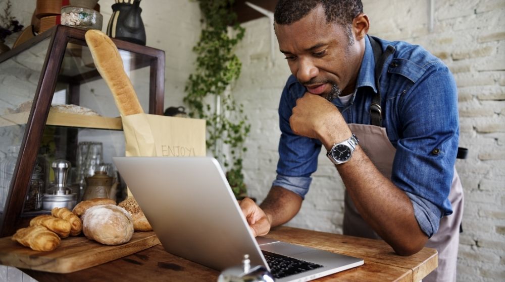 Man using devices for online business order at bakehouse | Feature | How Food Businesses Stay Up To Date During Covid-19