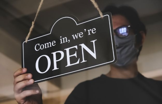 man with face mask turning a sign on a door shop | Update Information | Update Information | The Importance of Updating Your Business Description During Covid-19