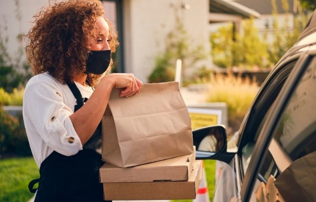 Girl handing the take out order - A Recap on GMB Changes Due to Covid 19 | Important Changes to Google My Business due to COVID-19