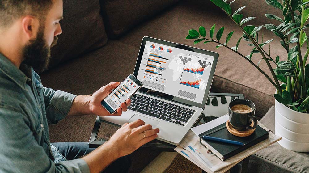 man using phone and laptop to see business analysis