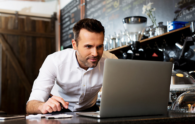 Smiling man looking at laptop | Improve Your Multi-Location Business Marketing With Locl