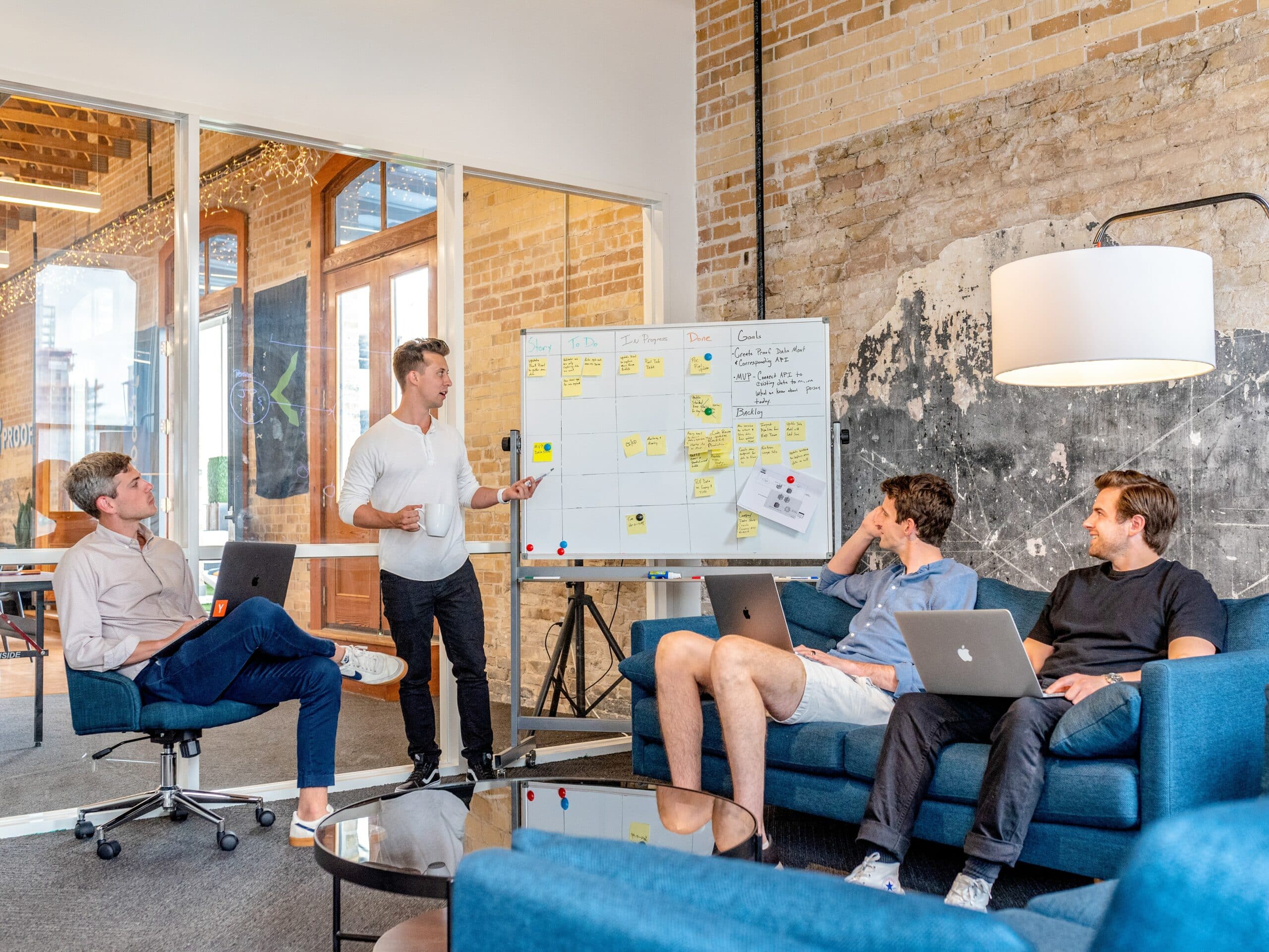 Group of 4 men in an office looking at a whiteboard full of notes